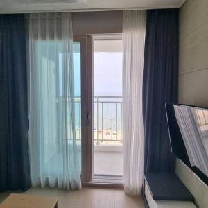 a room with a window with a view of a balcony at Yangyang Ocean Stay 환상적 전면 오션뷰 in Yangyang