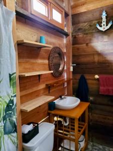 a bathroom with a wooden wall with a sink and a toilet at La posada de Mary in Montañita