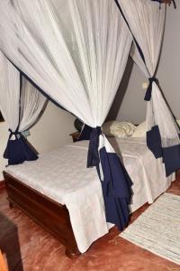 a bedroom with two beds with blue and white curtains at Villa ZAKIA in Madirokely