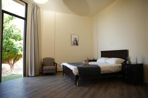 a bedroom with a bed and a chair and a window at The Ranch in Kfar Hazîr