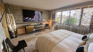 - une chambre avec un lit et une télévision murale dans l'établissement La Maison du Passage - Chambres - Suites premium, Spa, Piscine et Restaurant, à Martignargues