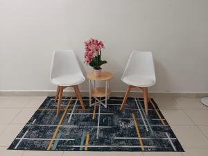 two white chairs and a table with a vase of flowers at Afna Homestay 2 in Kuala Lipis