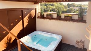 un bain à remous sur un balcon avec des plantes en pot dans l'établissement La Maison du Passage - Chambres - Suites premium, Spa, Piscine et Restaurant, à Martignargues