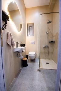 a bathroom with a toilet and a sink and a shower at Rikia Deluxe Houses in Vromonérion