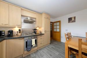 a kitchen with wooden cabinets and a wooden table with a dining room at Super Prime East Coast Explorer - Inverkeithing in Inverkeithing