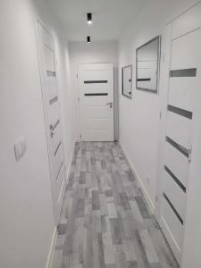 korytarz z dwoma białymi drzwiami i podłogą wyłożoną kafelkami w obiekcie Apartament NIKOLA w Wadowicach