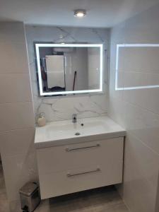 a white bathroom with a sink and a mirror at Apartament NIKOLA in Wadowice