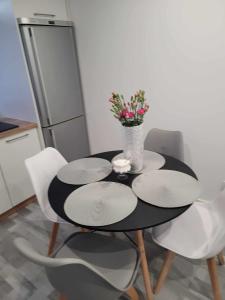 una mesa negra con sillas blancas y un jarrón con flores en Apartament NIKOLA en Wadowice