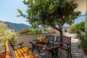 une table et des bancs sur une terrasse avec un arbre dans l'établissement Lemon Casa, à Skopelos