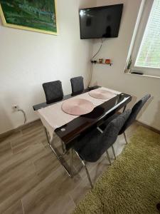 a dining room table with chairs and a flat screen tv at Vikendica Vrba in Gacko