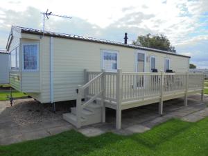 uma casa móvel com um alpendre e um deque em Kingfisher : Seabreeze:- 6 Berth, Enclosed veranda, Close to site shop em Ingoldmells