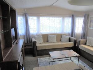 uma sala de estar com um sofá e uma mesa em Kingfisher : Seabreeze:- 6 Berth, Enclosed veranda, Close to site shop em Ingoldmells