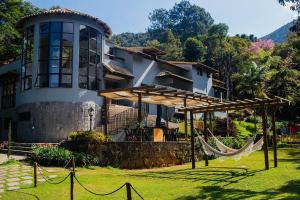 uma casa com uma rede em frente em Quinta da Torre 7 suítes Cachoeira SPA aquecido em Petrópolis