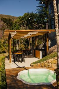 un patio con bañera de hidromasaje bajo una pérgola de madera en Quinta da Torre 7 suítes Cachoeira SPA aquecido, en Petrópolis