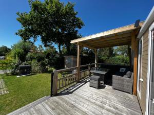 a wooden deck with a pergola on a house at De Strandhoed Renesse, new & luxe chalet with garden en close to centrum & beach! in Renesse