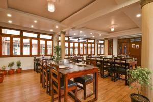 HOTEL INDIANA في شيلونغ: مطعم بطاولات وكراسي خشبية ونوافذ