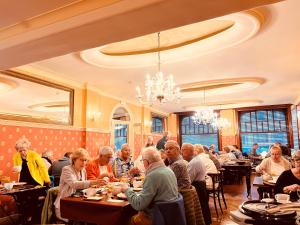 Eine Gruppe von Menschen sitzt an Tischen in einem Restaurant in der Unterkunft Avenue Hotel by F-Hotels in Blankenberge