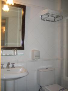 a bathroom with a sink and a toilet and a mirror at Hostal Canovas in Cuenca