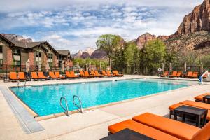 SpringHill Suites by Marriott Springdale Zion National Park في سبرينجديل: مسبح في فندق وكراسي برتقال وجبال