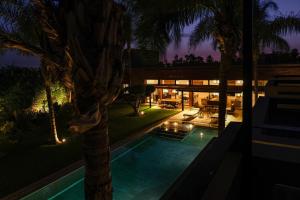 馬拉喀什的住宿－VILLA STANISLAS GOLF RESORT AL MAADEN，一座建筑前的游泳池,里面种着棕榈树
