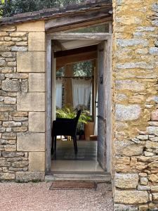 an open door into a stone building with a chair at Les Maisons d'Antan 5 étoiles in Saint-Geniès