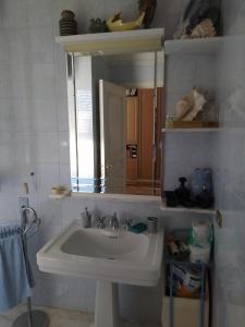 bagno con lavandino bianco e specchio di Dimora Maria a Copertino