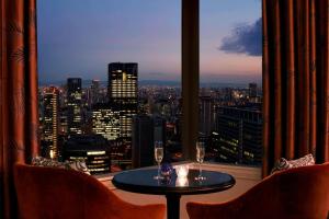 um quarto com uma mesa e cadeiras e vista para a cidade em The Ritz-Carlton Osaka em Osaka