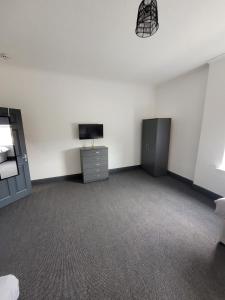 a white room with a tv and a dresser at The Goldmine Rooms in Hale