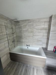 a bath tub in a bathroom with a tile wall at The Goldmine Rooms in Hale