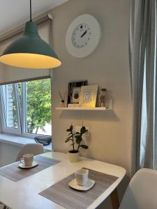 una mesa con dos tazas y un reloj en la pared en New Modern Apartments in the City Center en Narva