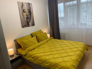 a bed with a yellow comforter in a bedroom at Victoriei Boulevard Private Apartment in Braşov
