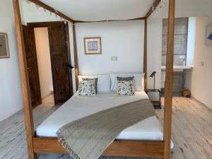 1 dormitorio con cama con dosel, sábanas y almohadas blancas en Casale Osvalda, en Alfiano Natta