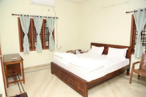 um quarto com uma cama com lençóis brancos e uma cadeira em The Nest Lovely 3BHK and 1BHK Villa em Chennai