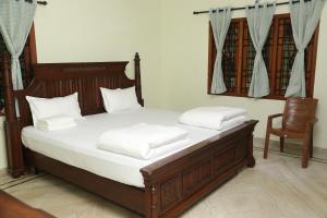 a bedroom with a bed with white sheets and a chair at The Nest Lovely 3BHK and 1BHK Villa in Chennai