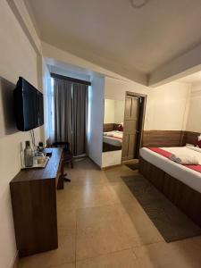 ein Hotelzimmer mit einem Bett und einem TV in der Unterkunft HOTEL INDIANA in Shillong