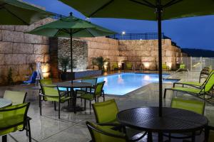 a patio with tables and chairs and a swimming pool at SpringHill Suites by Marriott San Antonio Northwest at The RIM in San Antonio