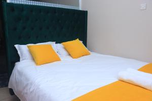 1 cama grande con 2 almohadas amarillas. en JAYBE STAYCATION en Nairobi
