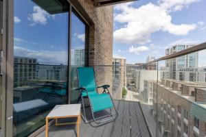 a chair on a balcony with a view of a city at Dockside Apartment With Scenic Views in London