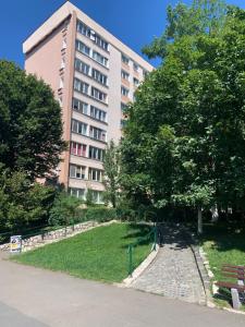 a building with a park with a bench and trees at Victoriei Boulevard Private Apartment in Braşov