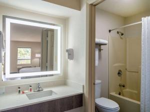 a bathroom with a sink and a toilet and a mirror at Days Inn by Wyndham Clemson in Clemson