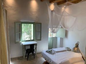 a bedroom with a bed and a desk and a window at Mandri B&B in Serifos Chora