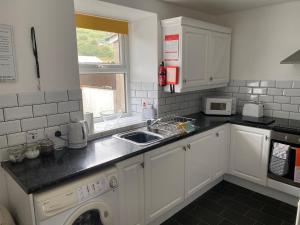 a kitchen with white cabinets and a sink at Antur Cottage in Blaenau-Ffestiniog