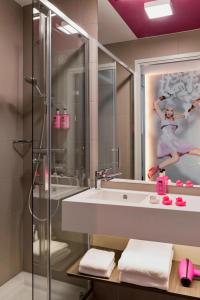 a bathroom with a shower and a sink and a mirror at MOXY Vienna Airport in Schwechat