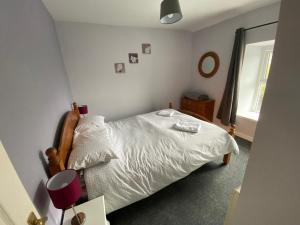 a bedroom with a white bed and a window at Antur Cottage in Blaenau-Ffestiniog