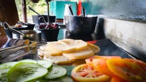 a tray with slices of cheese and tomatoes and cucumbers at Singharaja Garden AGRO ECO Lodge in Pelawatta