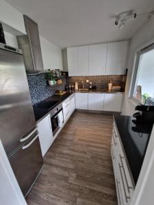 cocina con armarios blancos y suelo de madera en Large apartment - Perfect for Aqua Nor, en Trondheim