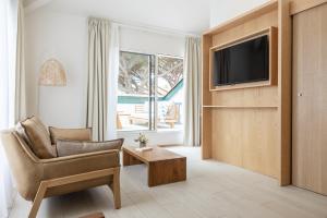ein Wohnzimmer mit einem Stuhl und einem TV in der Unterkunft Hôtel Ibaia in Hendaye