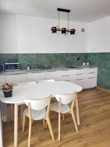 a kitchen with a white table and white chairs at Apartament Jezioro w sercu Ostródy in Ostróda
