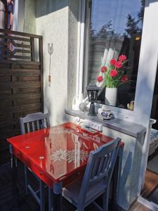 a red table and chairs on a patio with a window at Apartament Woda Morska in Ustka