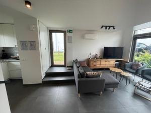 een woonkamer met een bank en een tv bij Maison Coxyde in Koksijde